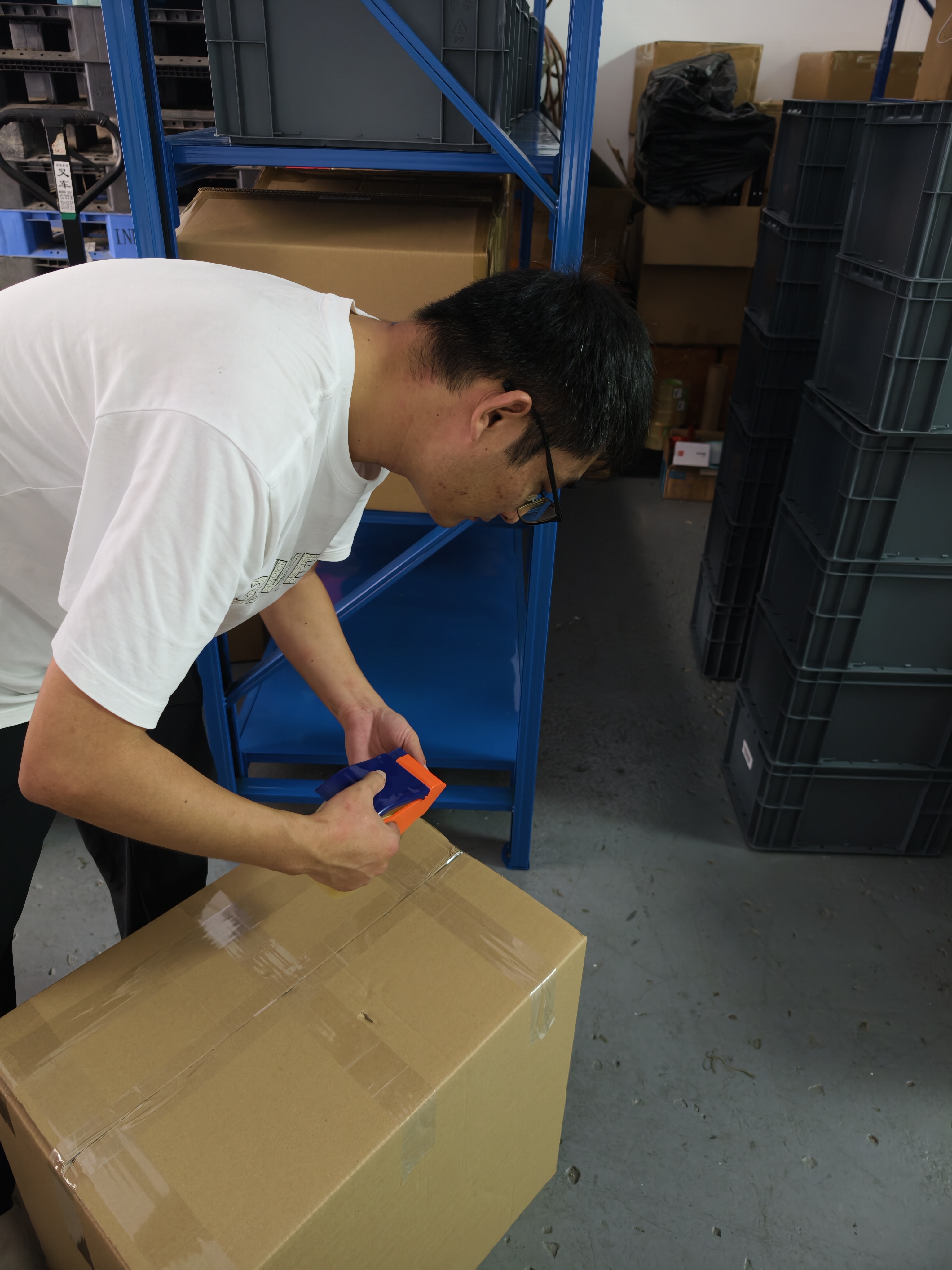 Warehouse worker sealing a carton with packing tape